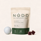 A stand-up pouch of NODD Golf Performance Chews in Wild Berry flavor, shown on a light beige background with a golf ball and two dark berry chew cubes.